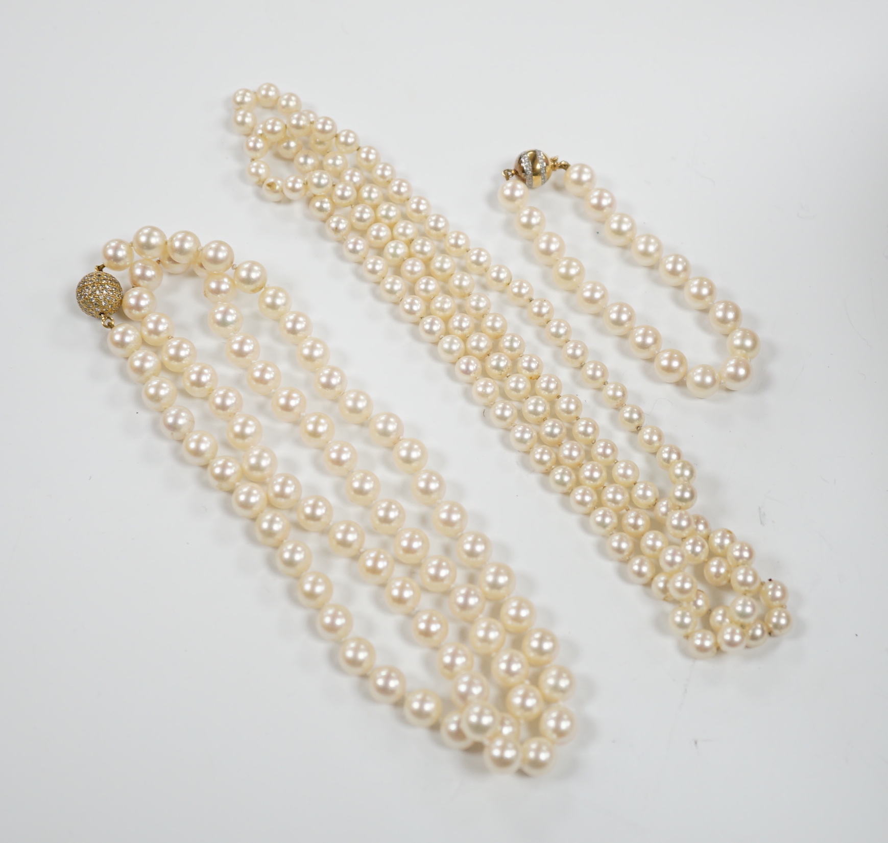 A single strand cultured pearl necklace, with diamond chip set 18ct gold clasp, 74cm and similar bracelet with diamond mounted clasps together with another cultured pearl necklace.